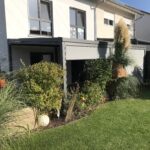 Weikum Überdachung - Ein Haus mit Gras und Pflanzen im Hof.
